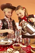 Two children at a party buffet pouring tea