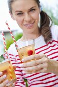 A girl holding two glasses of orangeade