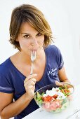Young woman eating feta salad