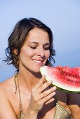 Junge Frau isst ein Stück Wassermelone im Freien