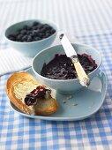 Blueberry jam in a small bowl and on bread