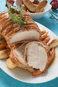 Bacon-wrapped turkey breast (partly carved) on root vegetables