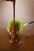 Coating a slice of kiwi fruit in couverture chocolate