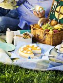 Picnic with fruit in picnic basket and mango cheesecake