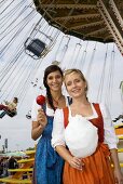 Two women with toffee apple & candy floss by swing ride(Oktoberfest)
