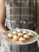Girl holding a plate of lemon meringue tartlets