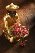 Gilded statuette with a bowl of pink pepper