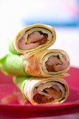Three wraps filled with salad leaves, ham and dried tomatoes