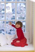 Girl sitting by window decorated with snowflakes