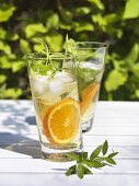 Drinks with lemon verbena and orange slices on table