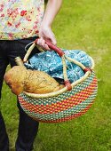 Person carrying picnic basket containing bread and wine