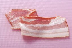 A rasher of bacon on pink background