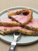 Slices of roast beef on plate with meat fork