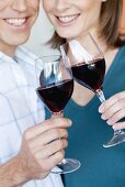 Smiling couple clinking glasses of red wine