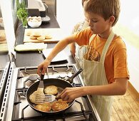 Two boys frying fish cakes