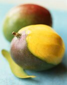 Two mangos, one partly peeled