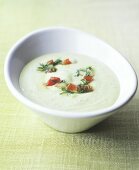 Avocado cream soup with pieces of tomato and dill