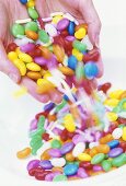 Coloured sweets falling out of someone's hands