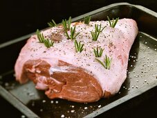 Leg of lamb studded with rosemary in roasting tin