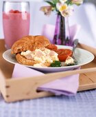 Croissant filled with ham and scrambled egg on a tray