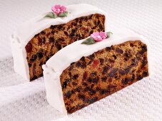 Two slices of fruit cake with white icing