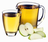 Apple juice in jug and glass and pieces of apple