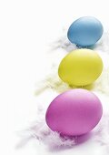 Three Easter eggs on white feathers