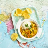 Fruity chicken curry on tray on map (India)