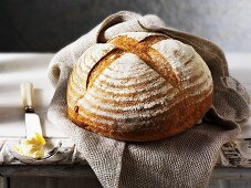 Round rustic bread on a jute bag, butter