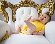 Baby in an ornate armchair with banana skin