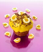Muffin mit gelbem Zuckerguss, Schokostreusel und Fruchtgummi