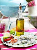 Raw prawns, chilli peppers, limes, olive oil and salt in front of table barbecue