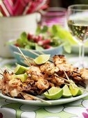 Grilled prawn skewers with lime wedges on plate