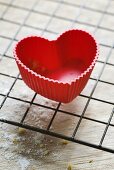 Red heart-shaped silicone baking mould on cake rack