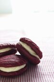 Three raspberry whoopie pies on a striped cloth