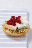 Half a bread roll topped with bean sprouts, blue cheese and cranberry compote