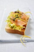 A slice of toast topped with salad, salmon and capers