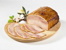 Sliced cold roast ham on a wooden plate