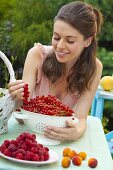 Young woman admiring a bunch of red currants