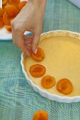 Woman placing apricots onto tart dough