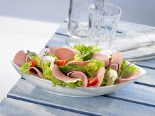 Kalte Platte mit Salatblättern, Geflügelwurst und Champignons