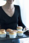 A lady serving vanilla souffles on a serving tray