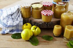 Mehrere Gläser Quittenmarmelade und frische Quitten