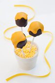 Cake Pops in Schokokuss-Form mit gelber Glasur im Becher mit gelben Zuckerperlen