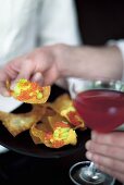 A Cosmopolitan and fried won ton sheets topped with avocado and trout caviar