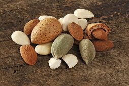 Almonds with and without shells on a wooden surface