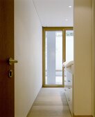 A view through an open door onto a terrace door and a cupboard under a bed