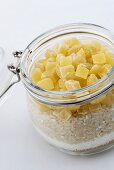 A jar of brown sugar, coconut shavings, rice and dried pineapple pieces