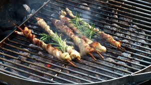Belly pork wrapped around skewers with rosemary on barbecue