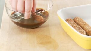 Preparing tiramisu: dunking sponge fingers in espresso